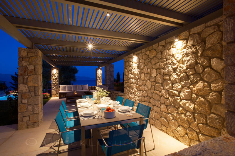 Outdoor dining area of a modern luxury villa with a pool in Lefkada