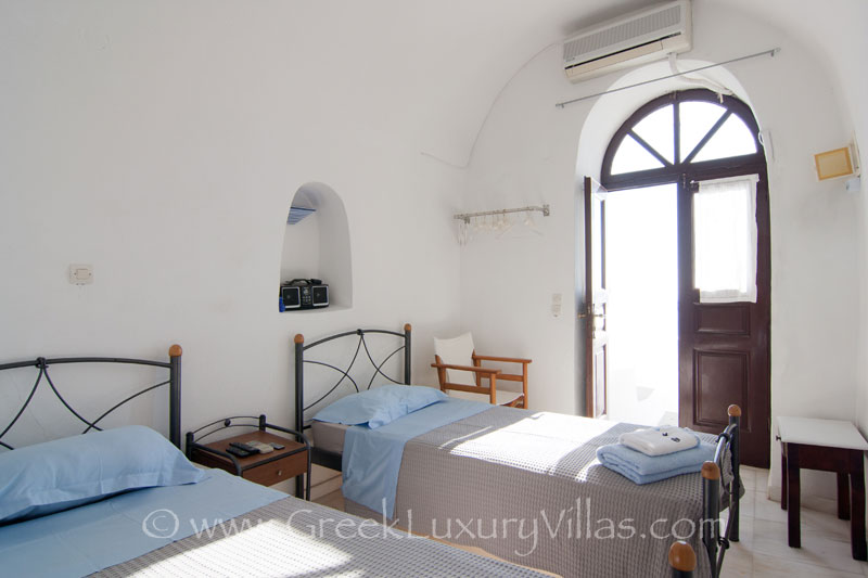 A twin bedroom in a large villa with a pool on the cliff in Santorini